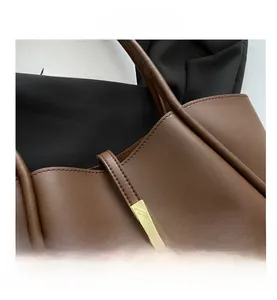 Dettaglio della borsa tote in pelle marrone con texture liscia e fibbia in metallo oro