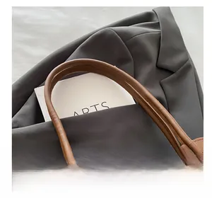 Dettaglio del manico imbottito di una borsa tote in pelle marrone con texture liscia