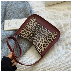 Detail of leopard print handbag with burgundy strap on knit texture background