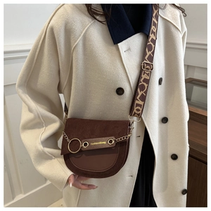 Gros plan d'un sac besace marron avec chaîne dorée et bandoulière large sur mannequin