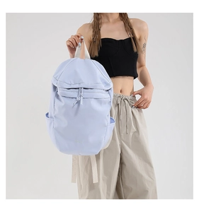 Detail view of a lightweight lilac nylon backpack with drawstring and front zip pocket