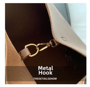 Dettaglio del gancio in metallo dorato e della trama in pelle marrone della borsa