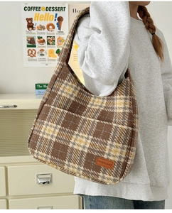 Close-up of brown plaid tweed tote bag with shoulder strap and leather patch detail
