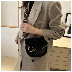 Détail d'un sac besace noir avec anneau doré et bandoulière tissée à motifs