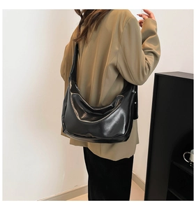 Borsa a spalla a mezzaluna nera lucida indossata da modella per uno stile trendy