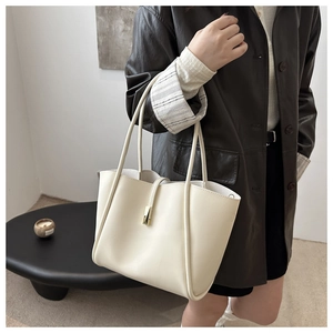 Dettaglio di una borsa tote bianco crema con fibbia metallica e giacca di pelle