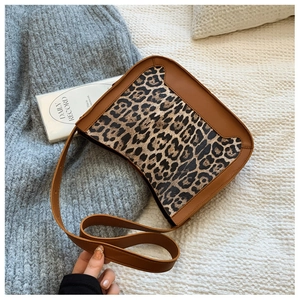 Detail of leopard print handbag with brown leather strap over a cozy knit blanket