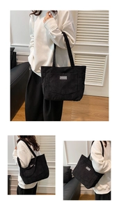 Detailed macro view of black corduroy tote bag showing ribbed texture and shoulder straps