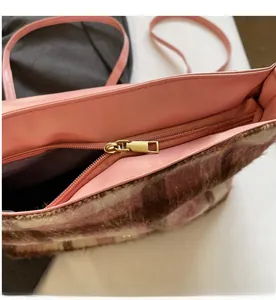 Détail d'une fermeture éclair dorée sur un sac à main en laine rose à carreaux avec doublure