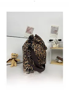 Detailed side view of the leopard print bucket bag featuring brown nylon shoulder strap