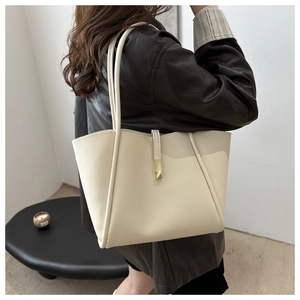 Dettaglio borsa tote color crema con hardware dorato indossata a spalla su giacca