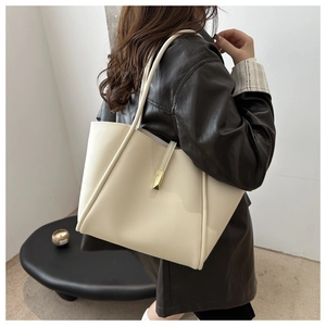 Vista dettagliata della borsa tote crema con elegante fibbia in metallo dorato lucido