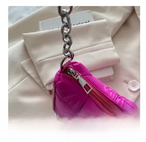 Détail du sac à main matelassé fuchsia avec chaîne argentée sur un blazer décontracté