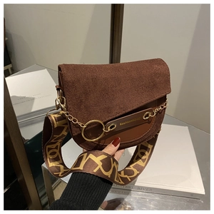 Détail d'un sac besace marron avec rabat en daim et large bandoulière à motifs