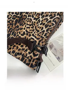 Close-up of leopard print bag featuring black metal hooks and brown fabric strap