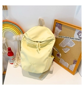 Detail of light yellow nylon backpack showing side pocket and white top handle