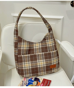 Close-up detail of the brown plaid tweed fabric and leather brand tag on the shoulder bag