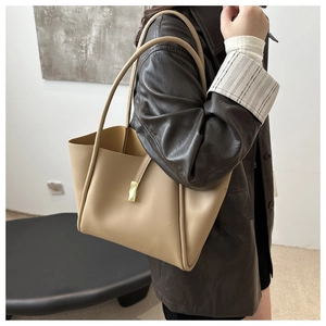 Vista laterale di un'elegante borsa tote in pelle beige indossata da una modella