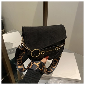 Détail du sac selle noir avec anneau doré et large bandoulière en jacquard géométrique