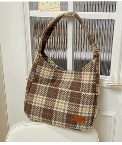 Close-up of retro plaid fabric and leather logo detail on a large tote bag