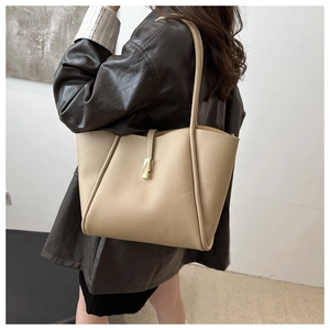 Dettaglio della borsa tote in pelle crema con fibbia dorata decorativa e tracolla lunga