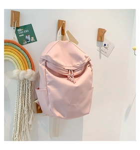 Detail of light pink nylon backpack featuring 'B.a.g' embroidery and side pockets