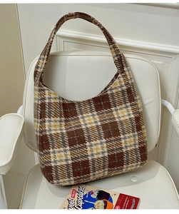 Detail of retro plaid hobo bag with thick wool texture on a stylish Nordic chair