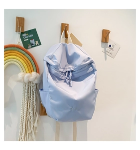 Detail of light blue nylon backpack with drawstring closure and front embroidery