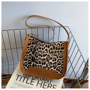 Detail view of leopard print handbag with brown leather trim and matte texture in metal basket