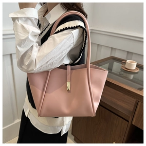 Elegante borsa tote rosa opaco con finiture dorate su un tavolo di legno curato