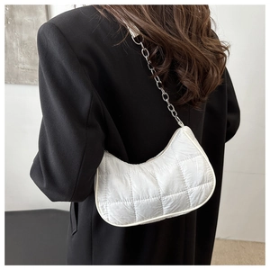Détail du sac blanc matelassé avec bandoulière chaîne argentée sur blazer noir