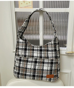 Close-up of checkered tweed hobo bag featuring black, white and orange pattern and leather tag