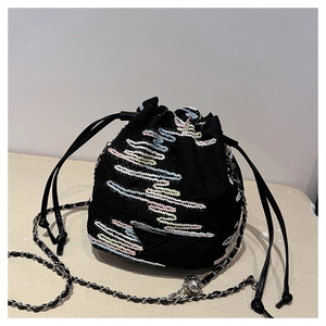 Detail of black canvas bucket bag featuring colorful embroidery and metal logo
