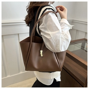 Vista dettagliata di una grande borsa tote in pelle marrone con ciondolo oro geometrico