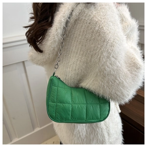 Détail d'un sac d'épaule en nylon vert matelassé avec chaîne argentée et texture bouffante