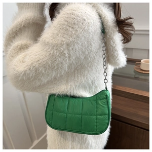 Détail du sac à bandoulière matelassé vert avec chaîne argentée sur pull en maille