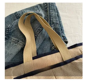 Détail du sac fourre-tout en velours côtelé beige avec liseré bleu marine et poignée