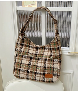 Detail of vintage plaid fabric texture and brown leather patch on large shoulder tote bag