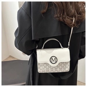 Detail of white and grey leather handbag with signature M logo metal buckle on black coat