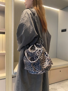 Detail of leopard print bucket bag with drawstring closure and wide nylon strap