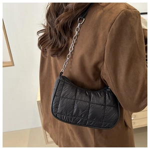 Détail du sac matelassé noir en nylon avec chaîne argentée sur l'épaule du mannequin