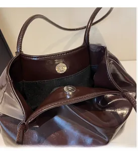 Detail of silver magnetic closure on vintage dark reddish tote bag with black lining