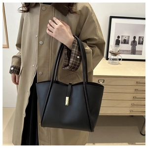 Dettaglio di una borsa tote in pelle nera opaca con una fibbia rettangolare in metallo dorato