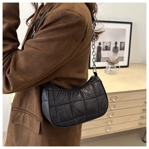 Détail du sac à bandoulière matelassé noir avec chaîne en argent et texture brillante