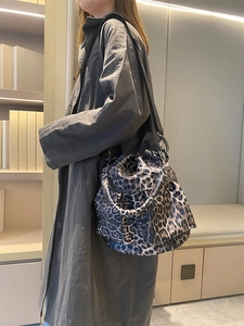 Detail of leopard print bucket bag with black strap worn over a stylish grey coat