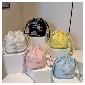 Detail of colorful embroidered drawstring bucket bags with chain straps in five trendy shades