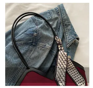 Close-up of burgundy leather tote bag handle with stylish geometric pattern scarf detail