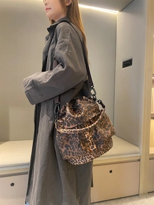 Detail view of leopard print bucket bag with drawstring closure on model in trench coat
