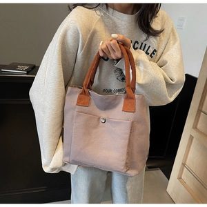 Détail du sac cabas en toile avec poignées orange et poche frontale à bouton pression