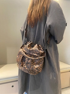 Detail view of leopard print bucket bag with multiple pockets worn by a model